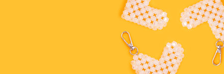 Banner with keychains in a heart shape made from acrylic beads on a yellow background.の写真素材