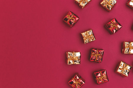 Christmas toys in a gift box shape scattered on a red background. Festive concept with copy space.の写真素材