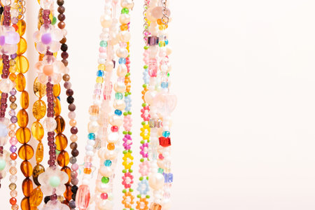 Colorful handcraft chains of beads, pearls and natural stones in front of beige background with copy space.の写真素材