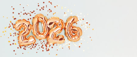 2026 New Year concept. Golden foil numbers balloons and shiny stars confetti on a blue background.