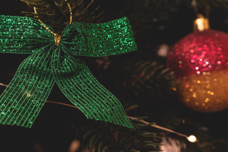 Closeup of green bow made from glittering ribbon hanging on a fir tree. Christmas handmade decorations.の写真素材