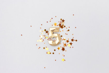 Golden number 5 and stars confetti on a blue background. Festive composition.の写真素材