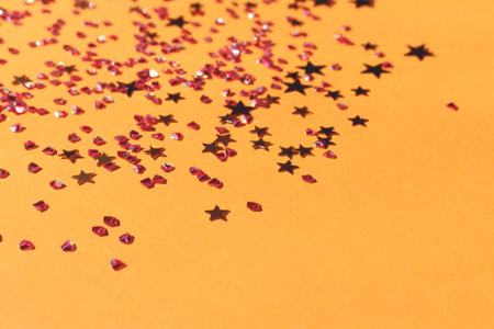 Shiny golden stars and crystals confetti on a yellow background. Selective focus.