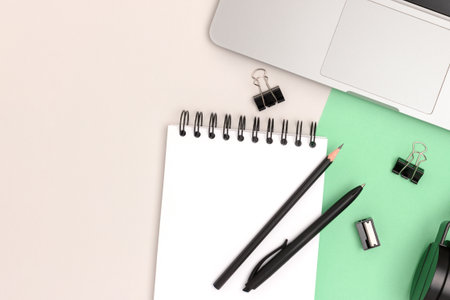 Workspace with laptop, headphones and stationery on mint and gray background. Online work concept...