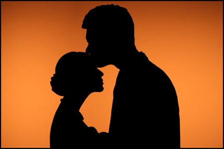 Black shape of kissing couple on orange background