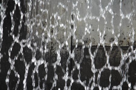 Close up of water falling aggressively from a fountain water  feature with concrete in the backgroundの写真素材