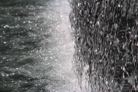 Water coming down from a water feature / fountain and aggressively hitting the pool of water below to create white waterの写真素材