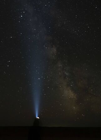 A female silhouette pointing a head-light on  the Milky Way direction - Gobi Desert, Mongolia