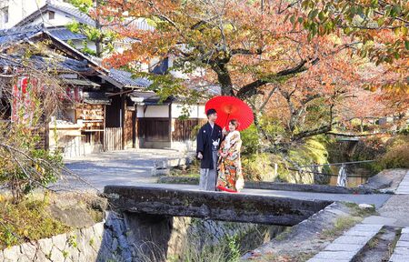 November 19, 2019: Kyoto Japan. Couple wearing Japanese traditional clothes with red umbrella at the Philosopher's Walk in Autumn - Kyoto, Japanのeditorial素材