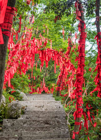 Red ribbon with written wishes hangging on the trees at Tianmen Mountain, The Heaven's Gate at Zhangjiagie, Hunan Province, China, Asiaのeditorial素材