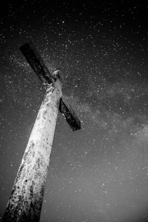A gloomy Cross That rises high and the starry sky with the Milky Way wonderful view from Mount Rocca Fiorita ME, Sicily, IT.の写真素材