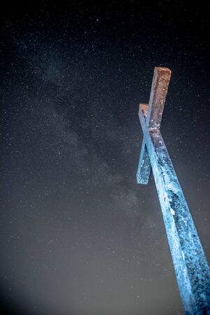A gloomy Cross That rises high and the starry sky with the Milky Way wonderful view from Mount Rocca Fiorita ME, Sicily, IT.の写真素材