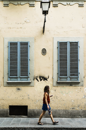 A girl walks through the streets of Florence. Una ragazza cammina per le vie di Firenze.のeditorial素材
