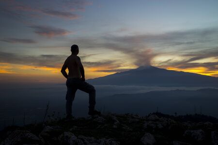 Self portrait. A shot that portrays me in observing my beloved Etna. The wonderful colors of the sunset seen from the Monte Veneretta (ME), Sicily, IT. Uno scatto che mi ritrae nell'osservare la mia amatissima Etna. I meravigliosi colori del tramonto vistの写真素材