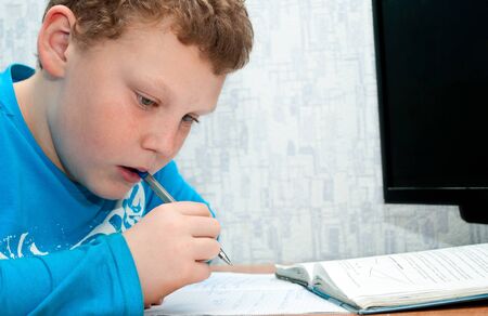 boy doing homework on mathematics in the room