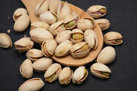 pistachio snack food on wooden spoon