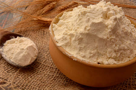 white flour in earthenware bowl with ears of wheat in the backgroundの写真素材