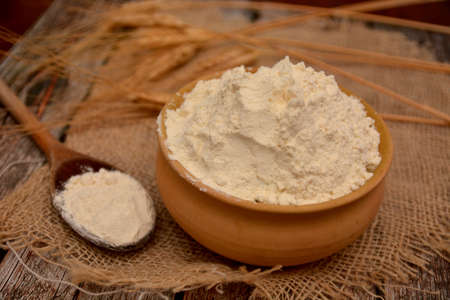 white flour in earthenware bowl with ears of wheat in the backgroundの写真素材