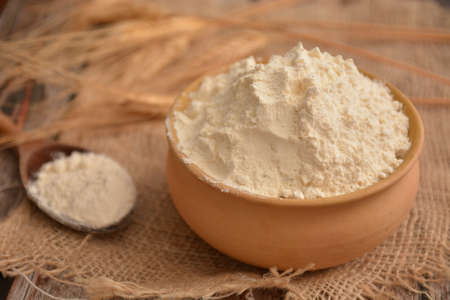 white flour in earthenware bowl with ears of wheat in the backgroundの写真素材
