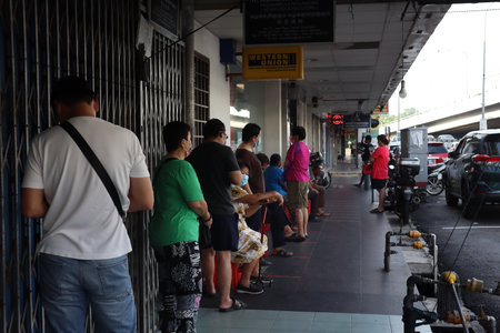 JOHOR, MALAYSIA-JUNE 23, 2021: Line up to enter the bank. During the Covid-19 Pandemic, people lined up outside banks, as banks controlled the number of people entering their premises.のeditorial素材