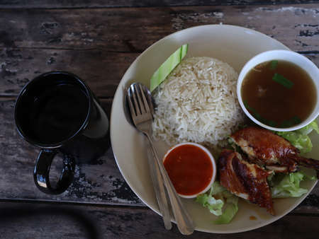 A plate of chicken rice with soup and a glass of water.の写真素材