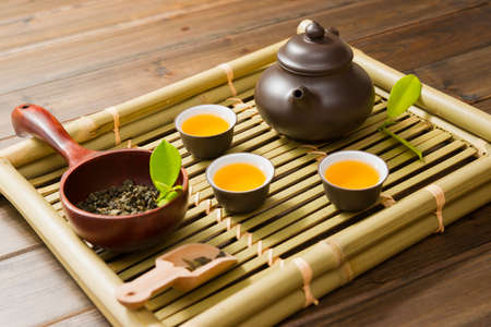 teapot,tea cup and tea leaves on a bamboo matの写真素材