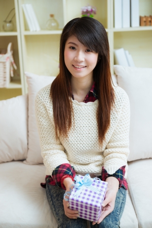 smiling young asian woman with a gift box at homeの写真素材