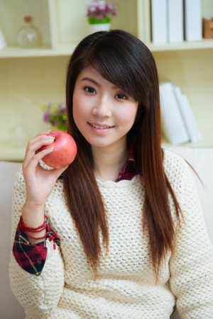 smiling young asian woman with apple at homeの写真素材
