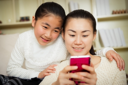 mother and daughter using a smart phone at homeの写真素材