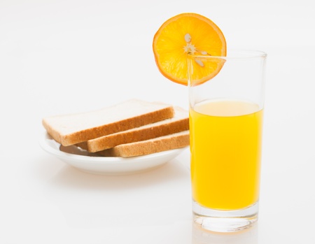 a cup of orange juice and bread on a white backgroundの写真素材