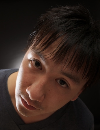 young asian man look at the camera in photography studio with black backgroundの写真素材
