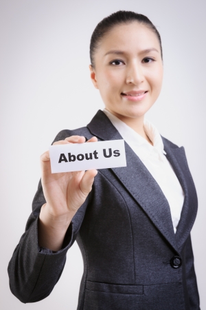 business woman with a paper card with "about us" on itの写真素材