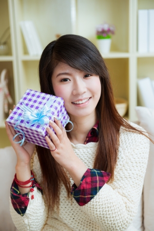 smiling young asian woman with a gift box at homeの写真素材