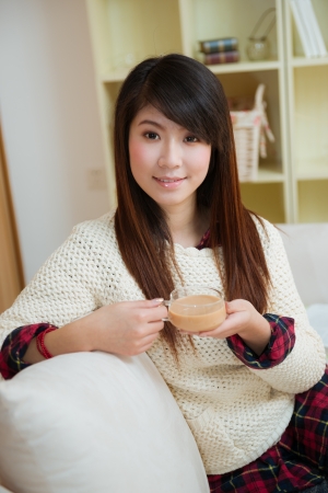 smiling young asian woman with coffee at homeの写真素材