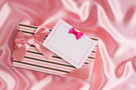 nice gift box and card on pink silk clothの写真素材