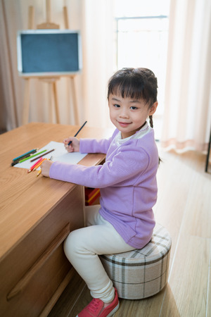 chinese little girl learn to draw on a paper with color pencilの写真素材