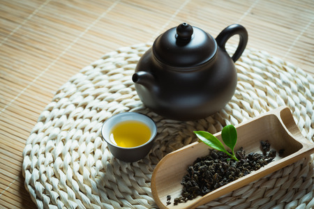 tea cup,teapot and tea leaves on straw mattressの写真素材