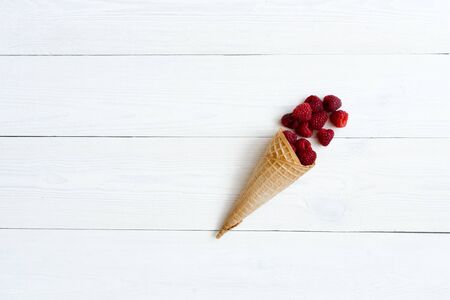 Cascade of fresh raspberries in a waffle cone of ice cream on a white background. Cafe or restaurant...
