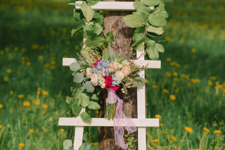 bright bride's bouquet on a white stepladder on a green grass backgroundの写真素材
