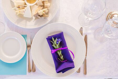 Served plate with Cutlery and a bright purple napkin with a sprig of eucalyptus in the decor of a wedding dinner or holidayの写真素材