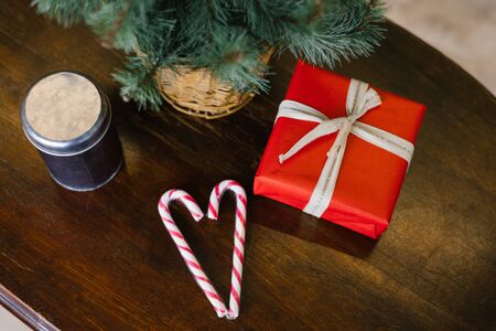 Christmas gift in red paper with a bow, two lollipops in the form of a heart on a wooden backgroundの写真素材
