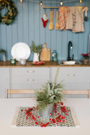Branches of spruce or pine in a metal decorative bucket on the kitchen table, decorated for Christmas and new yearの写真素材