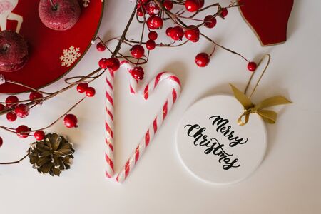 Christmas card, new year flat lay. Toy on the Christmas tree, candy and red berries on the branchの写真素材