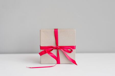Gift box tied with a bright pink purple satin ribbon on a gray background. Copy spaceの写真素材