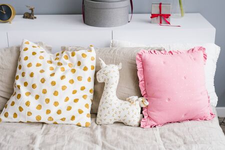 Soft toy unicorn on the bed with pillowsの写真素材