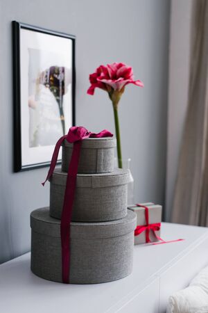 Round gift boxes tied with purple ribbon and a beautiful bright pink flower in the home decor for Christmas and New Yearの写真素材