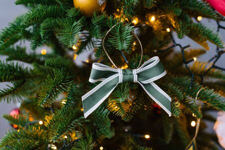 Green bow-toy on Christmas tree with lightsの写真素材