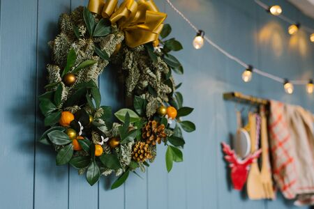 Christmas wreath hanging on blue annoyance wall with lights on it, decor apartment or kitchen in the houseの写真素材