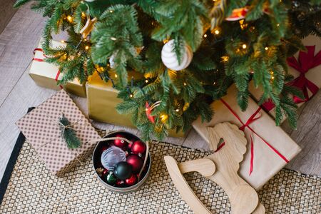 Gifts and a wooden horse lie under the Christmas treeの写真素材