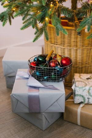 Metal basket with Christmas toys, gift boxes and gifts under the Christmas treeの写真素材